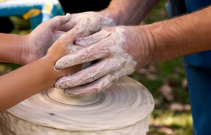 Potter Helps a Child Shape the Clay